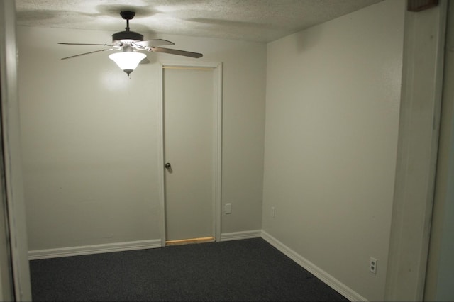 unfurnished room with a textured ceiling, dark colored carpet, a ceiling fan, and baseboards