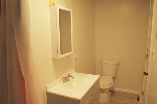 bathroom with baseboards, vanity, toilet, and wood finished floors