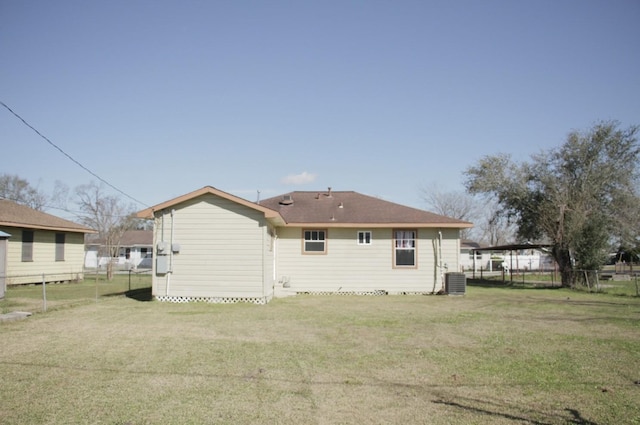 back of house featuring central AC, a lawn, and fence