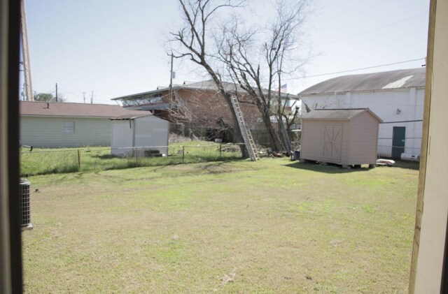 view of yard with an outbuilding, fence, and a storage shed