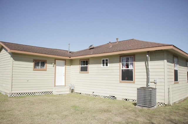 back of house featuring entry steps, roof with shingles, central AC unit, and a yard