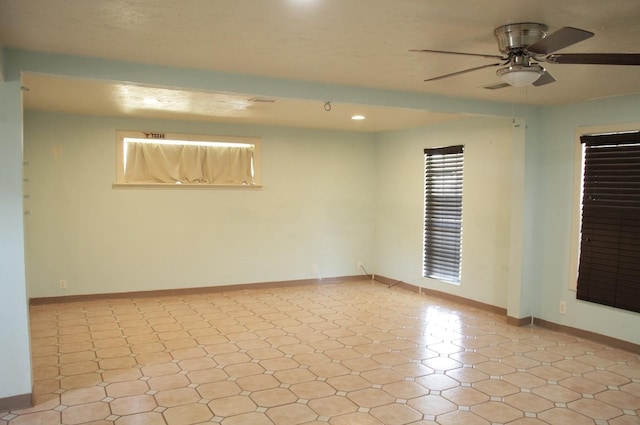 spare room featuring a ceiling fan and baseboards