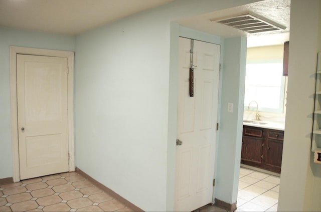 corridor featuring baseboards, visible vents, and a sink