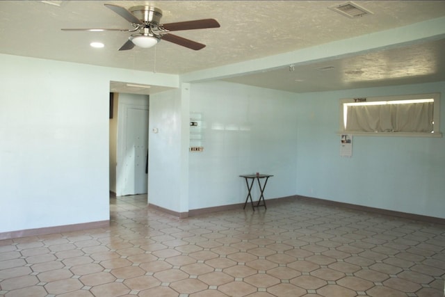 empty room with a textured ceiling, a ceiling fan, visible vents, and baseboards