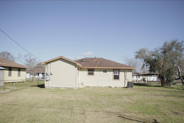 back of property featuring central AC unit, fence, and a yard