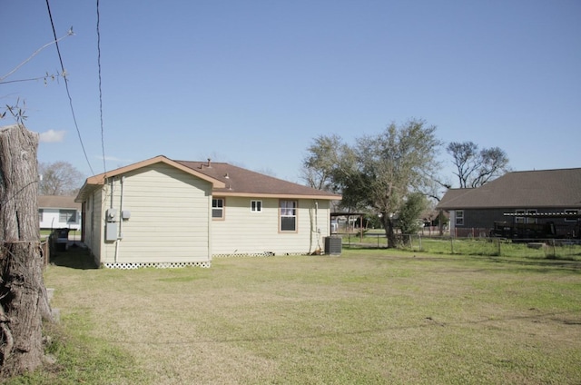 rear view of house featuring fence, cooling unit, and a yard