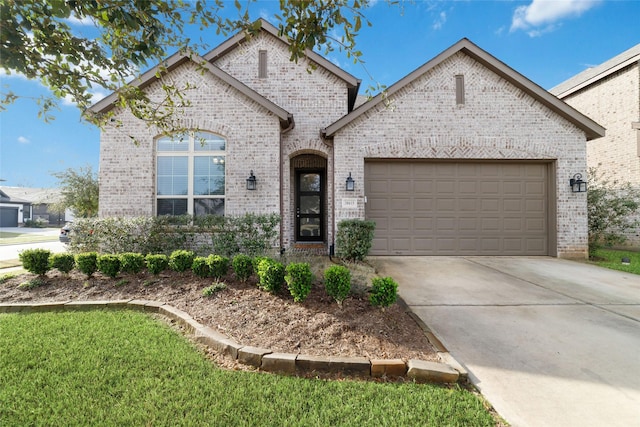 french provincial home featuring driveway, an attached garage, and brick siding