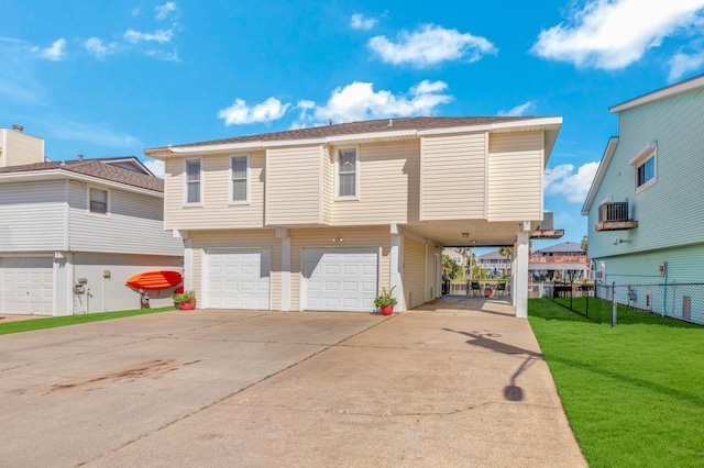 view of front of property with concrete driveway, a garage, fence, a carport, and a front lawn