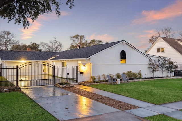 view of front facade featuring a shingled roof, a gate, fence, a yard, and brick siding