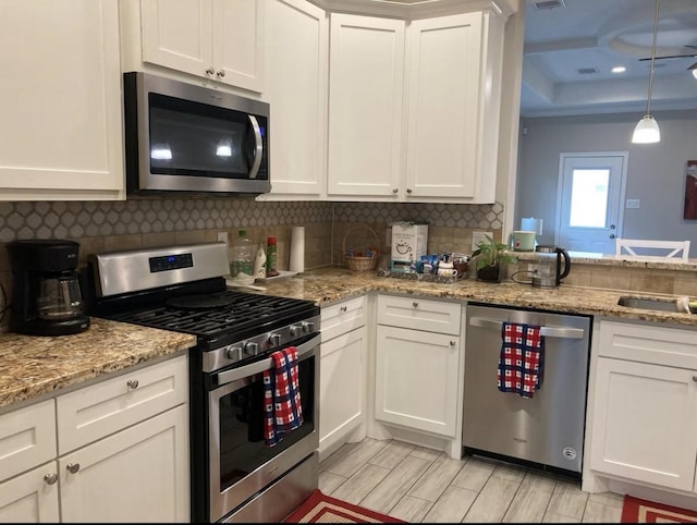 kitchen featuring appliances with stainless steel finishes, wood tiled floor, white cabinets, and decorative backsplash