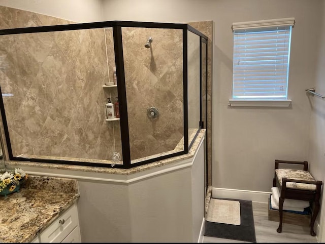 bathroom featuring a stall shower, vanity, baseboards, and wood finished floors