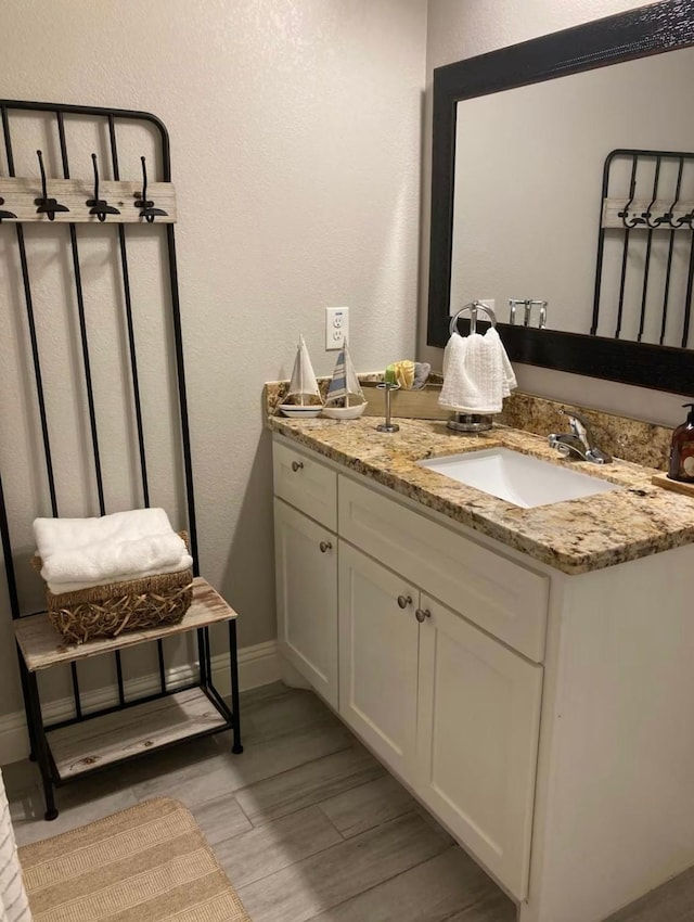 bathroom with baseboards, a textured wall, vanity, and wood tiled floor