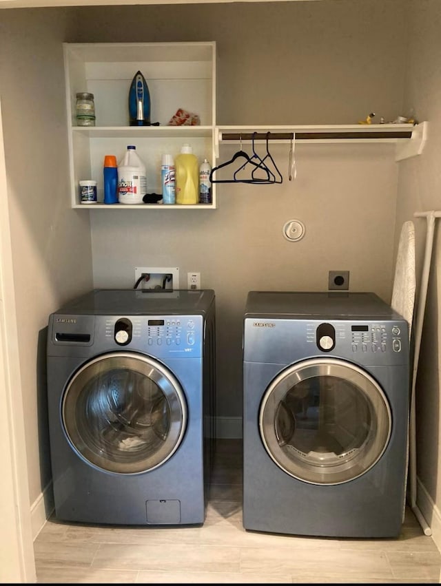 laundry area with wood tiled floor, laundry area, baseboards, and washing machine and clothes dryer