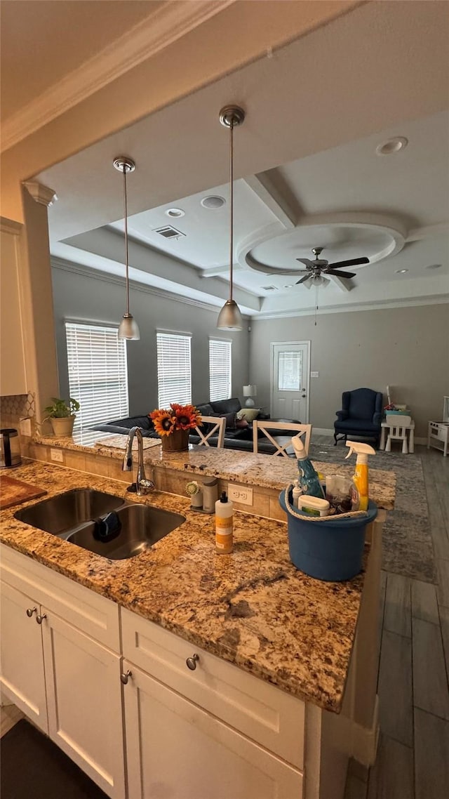 kitchen featuring crown molding, open floor plan, visible vents, and a sink