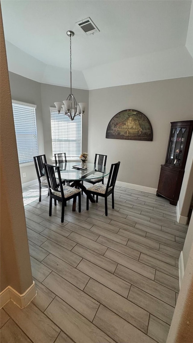 dining room featuring baseboards, visible vents, lofted ceiling, an inviting chandelier, and wood finish floors