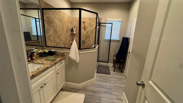 full bath featuring baseboards, a shower stall, and vanity