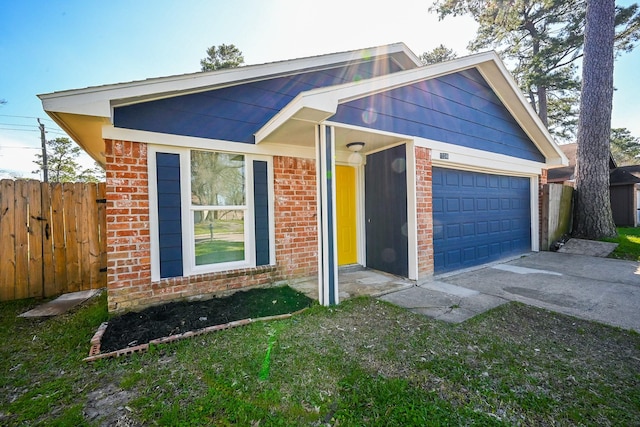 view of front of home with brick siding, fence, driveway, and an attached garage