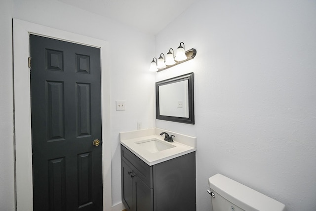 half bath featuring vanity and toilet