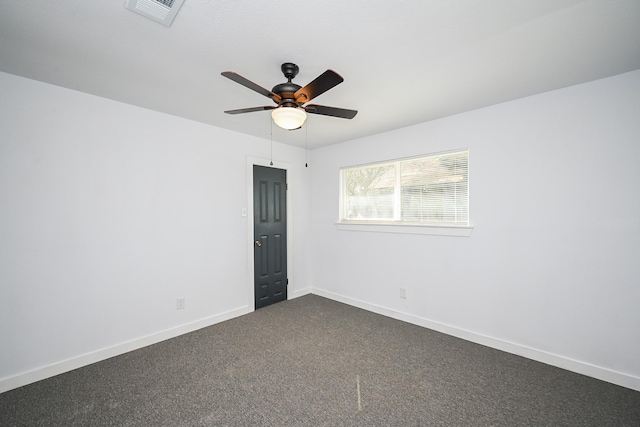 spare room with baseboards, visible vents, dark colored carpet, and a ceiling fan