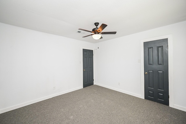 unfurnished room with dark colored carpet, a ceiling fan, visible vents, and baseboards