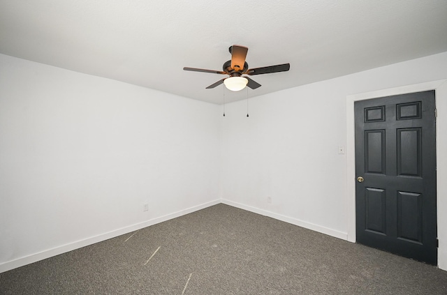 empty room featuring dark colored carpet, ceiling fan, and baseboards