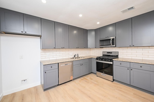 kitchen with light stone counters, visible vents, backsplash, appliances with stainless steel finishes, and light wood-style floors