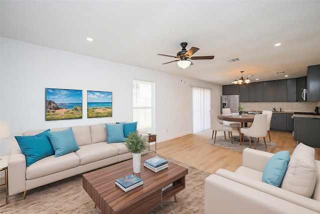 living room with ceiling fan with notable chandelier, recessed lighting, visible vents, and light wood-style floors
