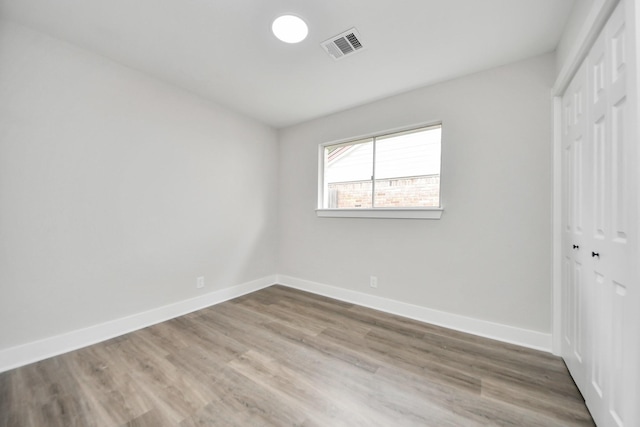 unfurnished bedroom featuring a closet, wood finished floors, visible vents, and baseboards