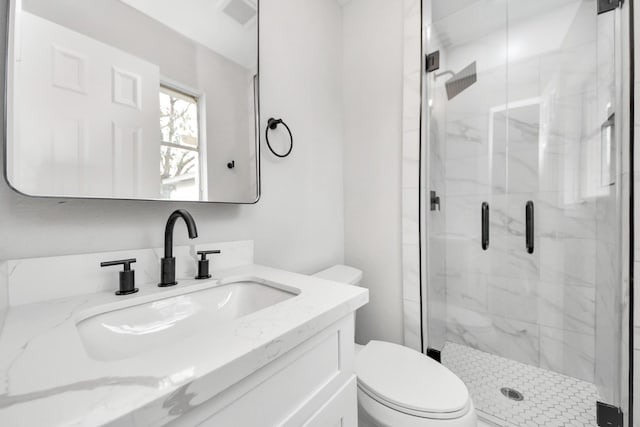 full bath featuring a marble finish shower, visible vents, vanity, and toilet