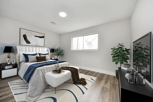 bedroom featuring wood finished floors, visible vents, and baseboards