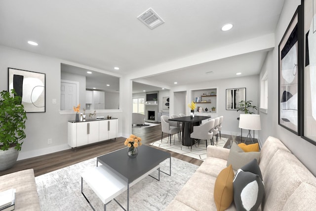 living room featuring recessed lighting, visible vents, a fireplace with raised hearth, and wood finished floors