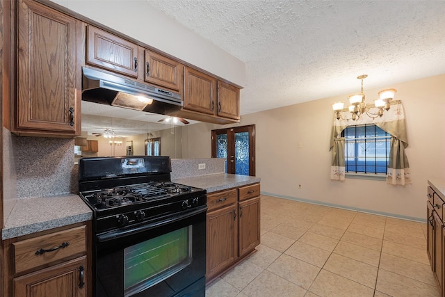 kitchen with a textured ceiling, brown cabinets, black gas range, and under cabinet range hood