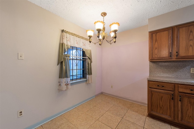 unfurnished dining area featuring a textured ceiling, light tile patterned floors, baseboards, and an inviting chandelier