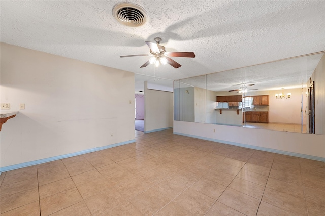 unfurnished living room featuring light tile patterned floors, baseboards, visible vents, a textured ceiling, and ceiling fan with notable chandelier