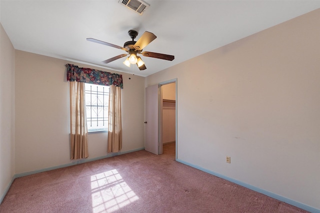 unfurnished bedroom with carpet, visible vents, a spacious closet, a ceiling fan, and baseboards