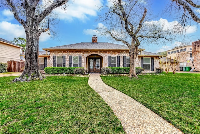 ranch-style house featuring brick siding, french doors, a chimney, and a front lawn