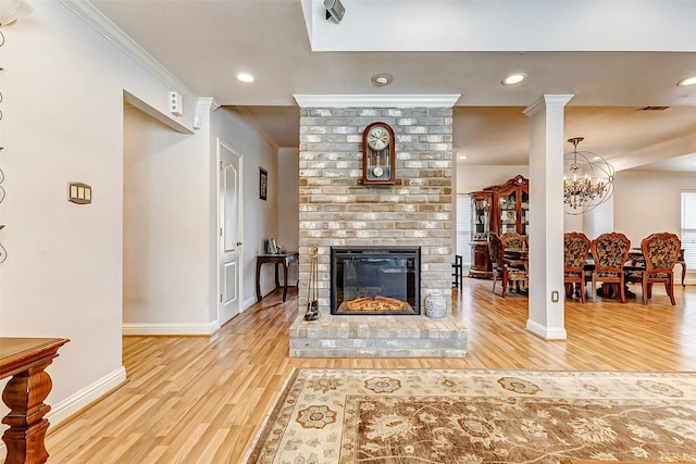 living area with a brick fireplace, wood finished floors, baseboards, and ornamental molding