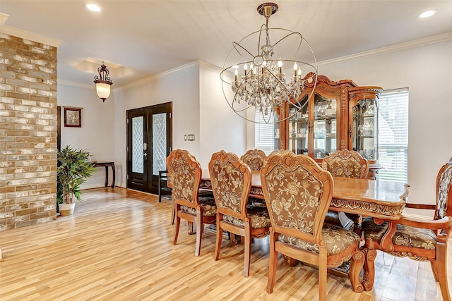 dining space featuring french doors, a chandelier, ornamental molding, and light wood finished floors