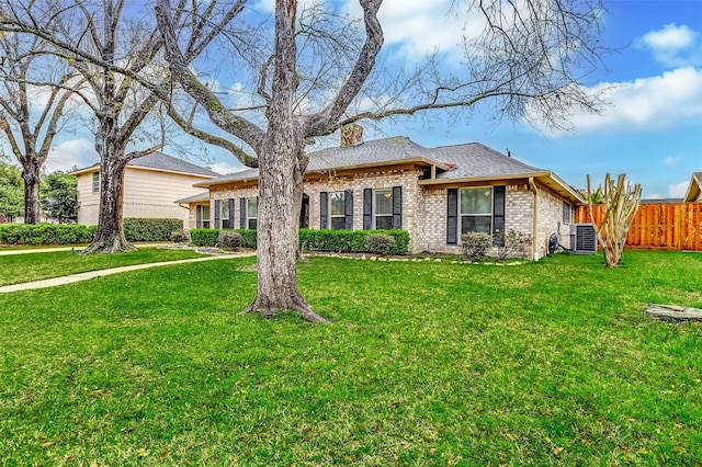 ranch-style home featuring brick siding, fence, roof with shingles, a front yard, and cooling unit