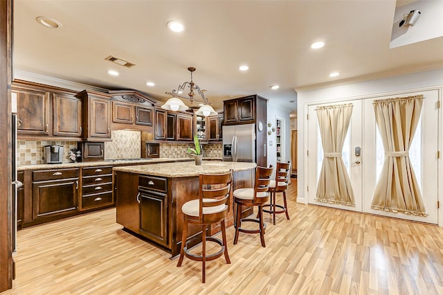 kitchen featuring visible vents, a breakfast bar, a kitchen island, stainless steel fridge with ice dispenser, and dark brown cabinets