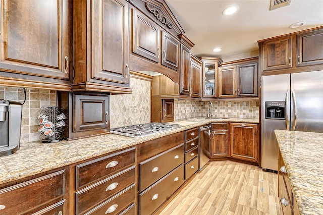 kitchen featuring a sink, decorative backsplash, appliances with stainless steel finishes, and light wood-style flooring