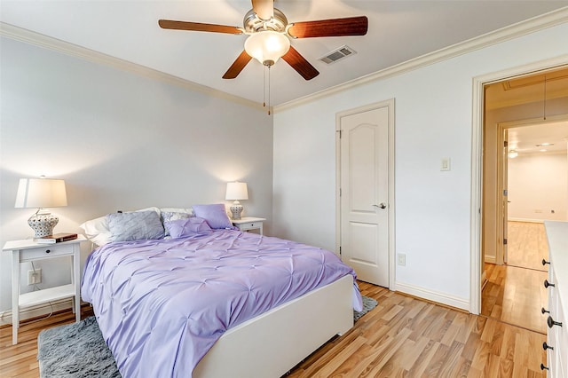 bedroom featuring attic access, light wood-style flooring, crown molding, and visible vents