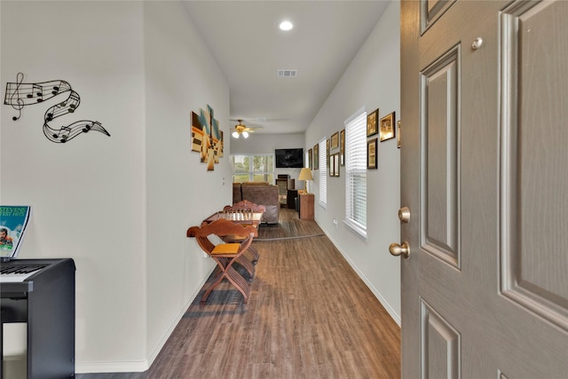 corridor featuring visible vents, baseboards, and wood finished floors