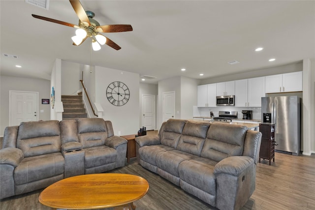 living area featuring recessed lighting, visible vents, stairway, and wood finished floors