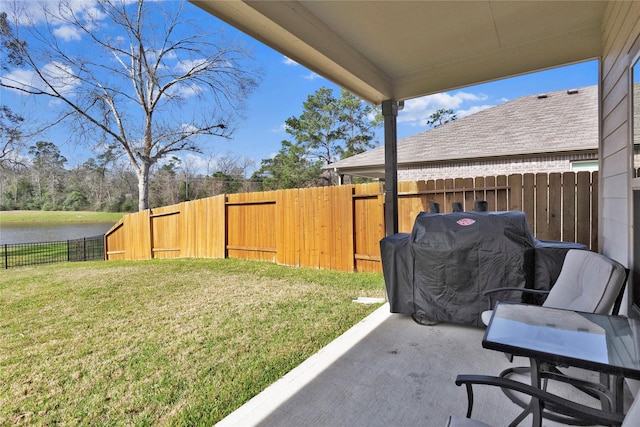 view of patio / terrace featuring a water view, a fenced backyard, and area for grilling