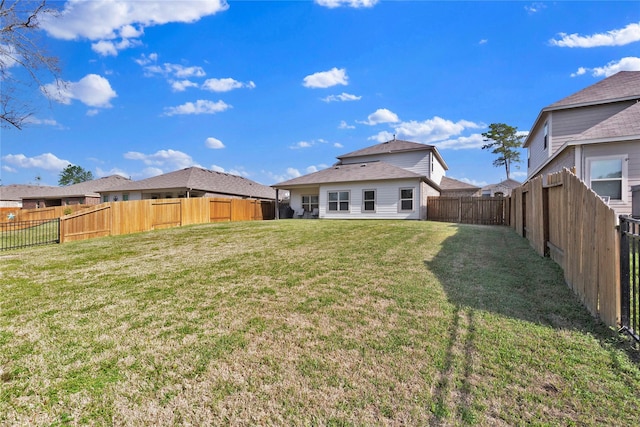 rear view of property featuring a fenced backyard and a lawn