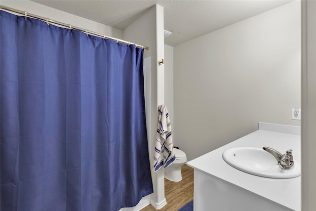 bathroom featuring a shower with shower curtain, toilet, a textured ceiling, vanity, and wood finished floors