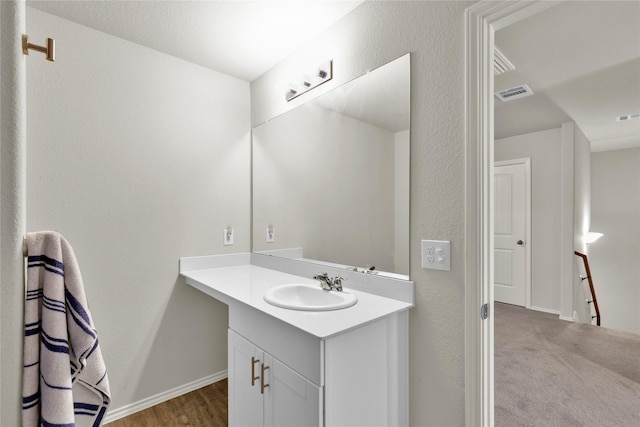 bathroom featuring a textured wall, baseboards, visible vents, and vanity