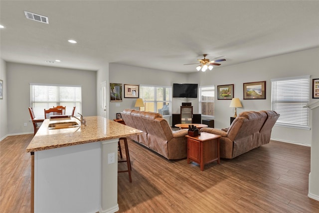 living area featuring a wealth of natural light, light wood finished floors, visible vents, and a ceiling fan