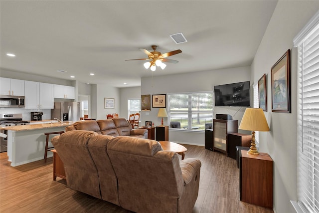 living area with ceiling fan, recessed lighting, wood finished floors, visible vents, and baseboards